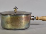 a metal pot with a wooden handle on a table