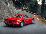 red sports car driving down the road in front of a rock wall