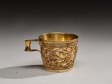 a gold cup with a handle on a white surface