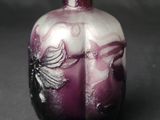 a purple vase with a bird on it on a black surface