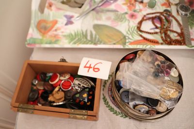 une boîte de boutons et une paire de ciseaux posés sur une table