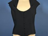 a black top on a mannequin stand against a blue wall