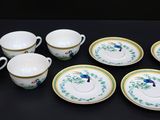 six tasses et une soucoupe posées sur une table noire
