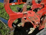 un tracteur immobilisé dans l'herbe, avec une charrue attelée derrière lui