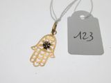 a small gold hamsa hand with a black stone on it
