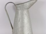 an old metal pitcher with a handle sitting on a table