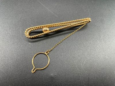 un collier en or auquel est suspendue une loupe