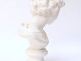 white marble bust of a boy with curly hair on a pedestal