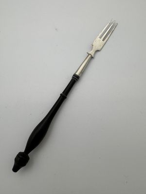 a fork with a black handle sitting on top of a white table