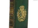 un vieux livre à la couverture verte posé sur une table blanche