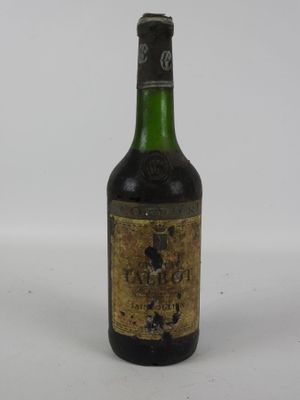 une vieille bouteille de vin posée sur une table blanche