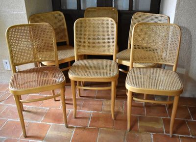 quatre chaises en bois assises sur un sol carrelé devant une porte