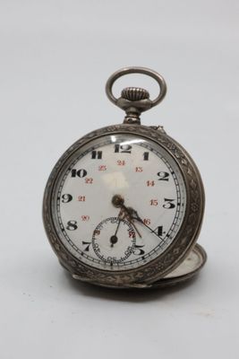 a silver pocket watch sitting on a white surface