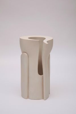 un vase blanc percé d'un trou, posé sur une surface blanche