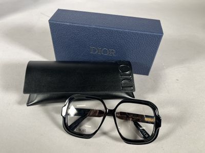 des lunettes et leur étui posés sur une surface blanche, avec une boîte bleue en arrière-plan