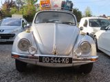 a silver vw beetle parked in a parking lot with other cars
