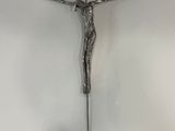 un crucifix en métal accroché au mur d'une pièce blanche