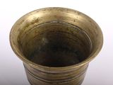 a gold vase that is sitting on a white surface