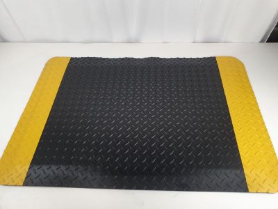 a black and yellow diamond plate mat on a white surface
