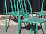 two green chairs sitting next to each other on the street