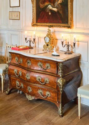 un tableau accroché au mur au-dessus d'une commode dans une pièce