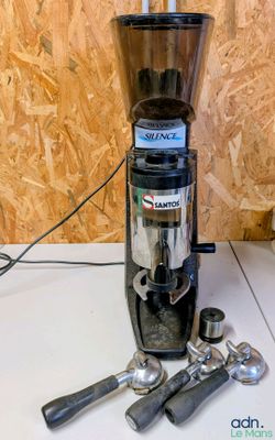 un moulin à café posé sur un plan de travail, à côté de quelques cuillères