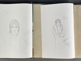 several books are lined up on a shelf with drawings on them