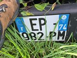 a person standing next to a license plate that is laying in the grass