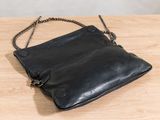 the small black purse is sitting on a wooden table
