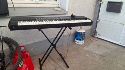a keyboard that is sitting on a stand in front of a window
