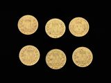 six gold coins with different designs on them on a black background