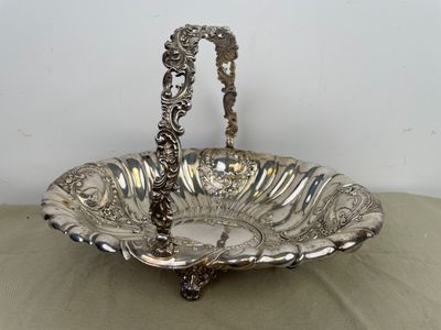 un plat ancien en argent avec une poignée, posé sur une table