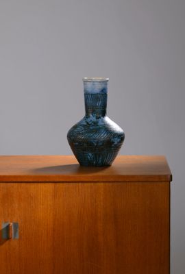 a blue vase sitting on top of a wooden cabinet