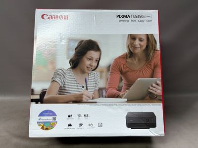 La boîte d'une imprimante photo Canon est ouverte sur la table.