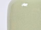 a green vase with a white base on a white surface
