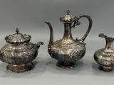 deux théières en argent et une cafetière posées sur une table