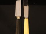 two knives are sitting next to each other on a black surface