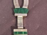 a necklace with a green pendant on it on a purple surface