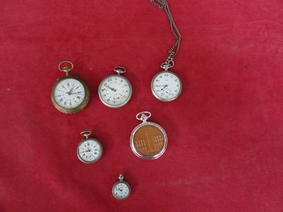 de nombreux modèles différents de montres de poche posés sur un tissu rouge