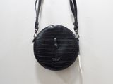 le sac à main noir est accroché à un mur blanc, avec une bandoulière noire