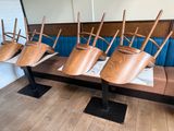 several wooden chairs are lined up on a bench in a restaurant