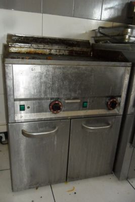une cuisinière argentée au milieu d'une cuisine carrelée de blanc