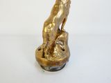 statue en laiton représentant un chien assis sur un rocher, sur fond blanc