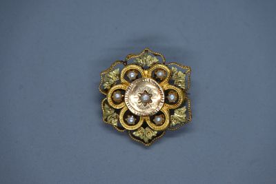 une image représentant une broche en or ornée de perles