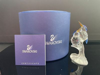 un petit oiseau en verre posé sur une table, à côté d'une boîte bleue