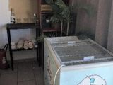 a small refrigerator in the corner of a room with a table and a chair