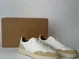 the white and tan sneakers are next to a cardboard box