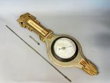 une horloge dorée posée sur un fond blanc, avec une aiguille