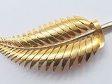 an image of a gold leaf brooch on a white surface