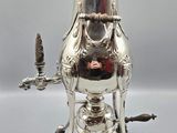an antique silver plated coffee pot with a bird on top